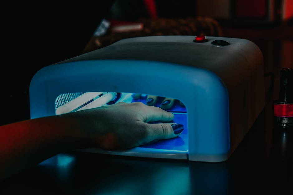 Glossy short gel-finish nails under a small UV lamp