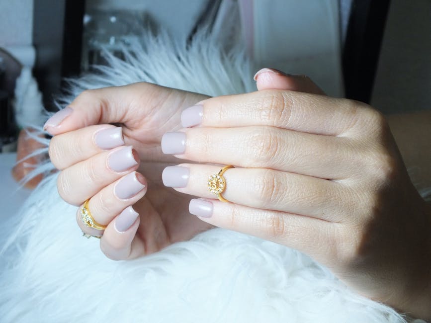 Pink press-on nails on a hand resting against a soft surface