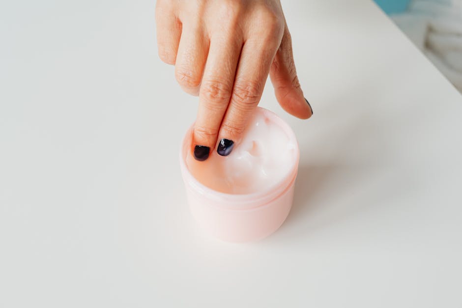 Fingers picking up moisturizing cream from a container