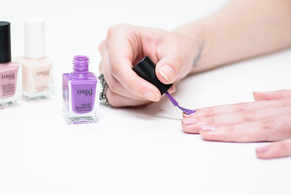 Hand applying purple nail polish at home