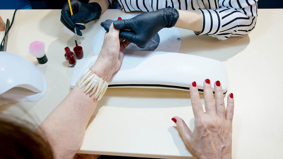 Manicurist applying nails on a client's hand
